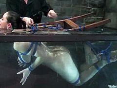 Brunette girl gets tied up to a bondage chair. After that the guy tortures her tits and toys her vagina. After that the guy puts immerses the chair with a girl in the water.
