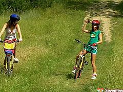 Two teens on bicycles decide to take a break. They start to fondle each other and finger fuck each other shaved pussies right on the grass.