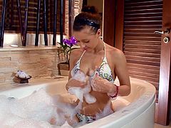 Lovely brunette girl takes a bubble bath. She gets so horny that starts to touch her tits and finger the pussy.