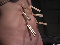 Busty brunette hottie gets crucified naked by pitiless domina before she proceeds to choking her belly, big firm tits and bald pussy lips with wooden clothing pegs in BDSM-involved sex video by 21 Sextury.