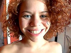 Cute redhead teen Sunny with beautiful blue eyes and curly hair takes off clothes slowly and gets filmed in point of while smiling during her first interview in living room.