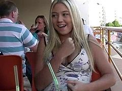 Amazing blonde girl drinks a cocktail in a cafe. You can easily see her juicy boobs because a t-shirt cannot hide them.