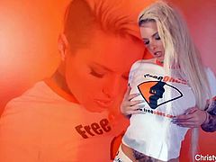 Christy Mack is wearing a regular top and posing in an orange room. She shows off her tattoos and she flashes her huge boobs as well. This is a sort of teaser.