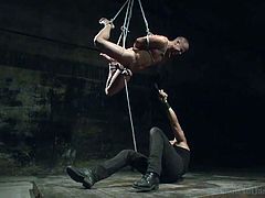 This gay slave hunk is tied up in rope and the master has hanged him from the ceiling. The slave has rope tightly wrapped around his cock and ball and the master give the rope a tug. This makes the gay slave sway back and forth.