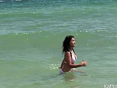 Happy smiling Asian brunette swims in the ocean and poses in her bikini