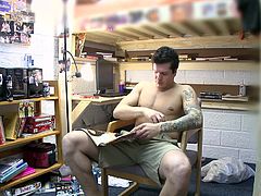 A hunky gay guy with short dark hair and a sexy tattooed body enjoys playing with his huge cock and balls in his bedroom.