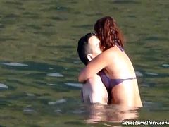 Couples in love making out in the water at a beach splashing water while bracing their arms filled with desires, orally sexually pumping up the blood flow.