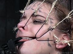 Jessica is in a very unique situation here. The young, beautiful, metal-mouthed slut is in an big oil drum with only her head exposed. Her executors have hooks attached to wires, which they are putting in her mouth, stretching and pulling her lips and nose. They also use a pair of tongs to pull her tongue.