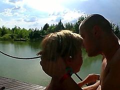 Blonde with huge tits is sucking a cock by the body of water. She loves it when her body is nude in the sun while she is taking on a hard dick.