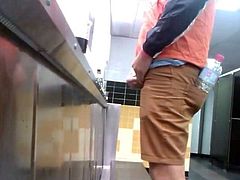 Guys in the urinals taking leak.